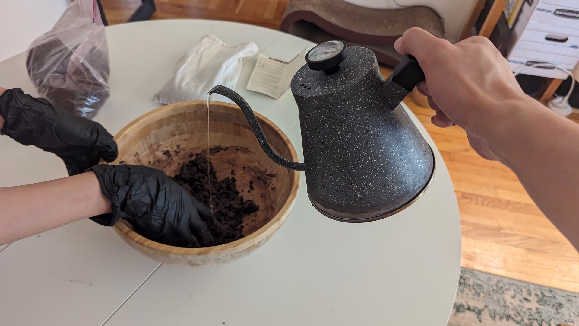 Adding water to the soil and clay mix in a wooden bowl